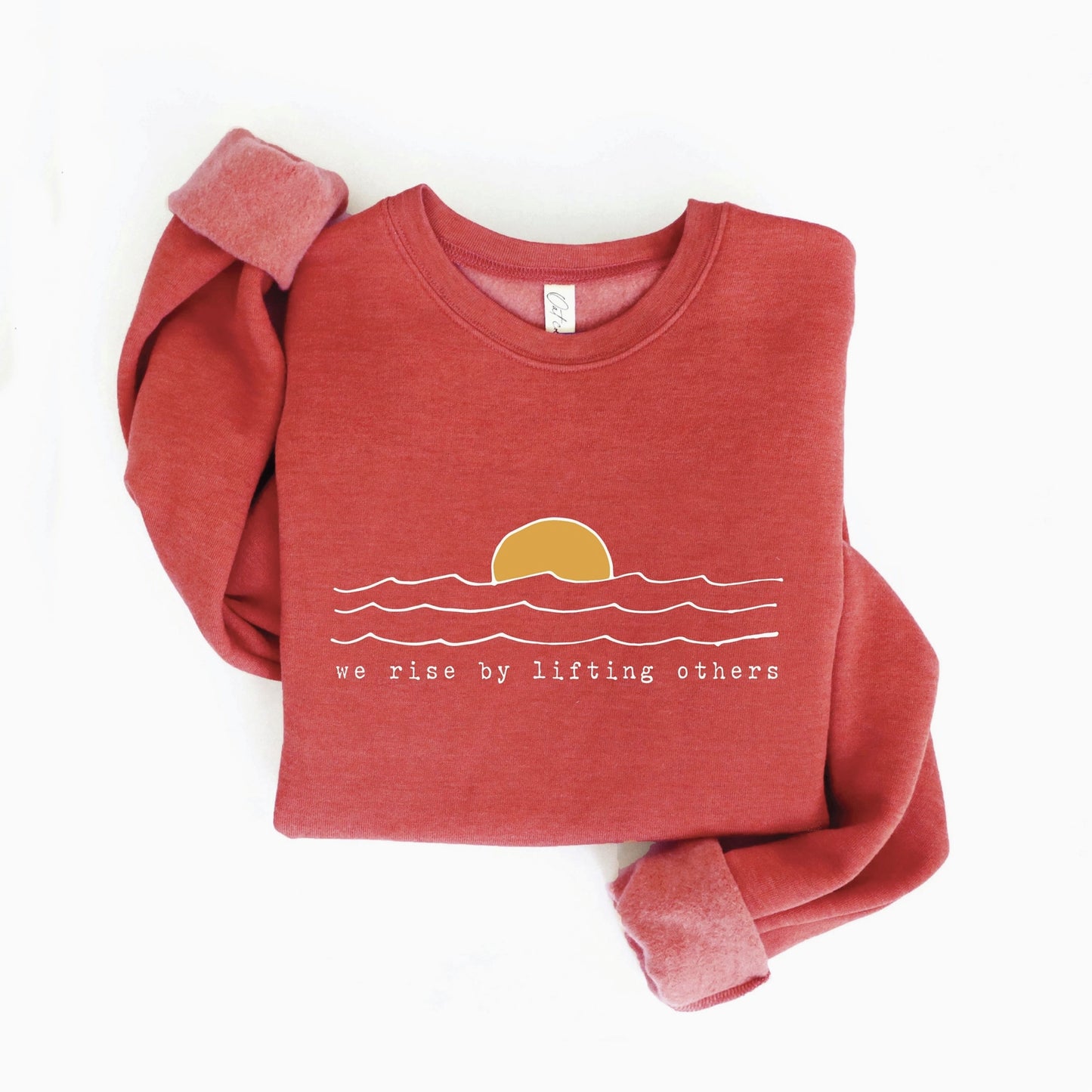 Shop our 'We Rise By Lifting Others' Sweatshirt. A whimsical, artisanal graphic pullover for slow living.