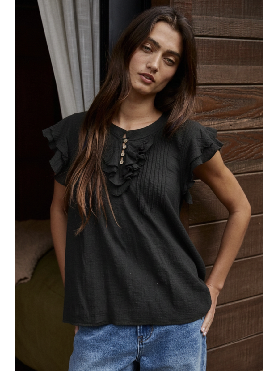Woman wearing a Black cotton-linen blouse featuring a ruffled V-neckline, button-front, pin-tuck pleats on the chest, and tiered flutter sleeves.